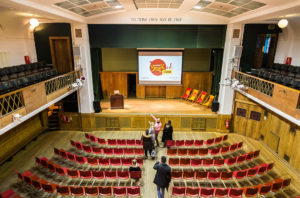 Conway Hall main hall set out for presentation, as a points the stage out to his guests.