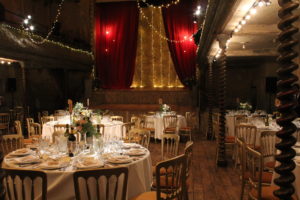 Wilton’s Music Hall set up with round wedding tables for seated dinner or private event, decorated with fairy lights.