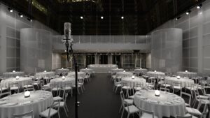 View from stage with microphone at The Pelligon at night, with the room set up with round tables for a seated dinner.